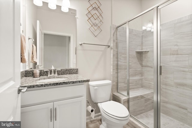 bathroom featuring vanity, a shower stall, and toilet