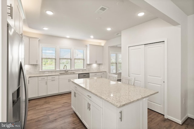 kitchen featuring appliances with stainless steel finishes, a sink, a center island, decorative backsplash, and dark wood-style floors