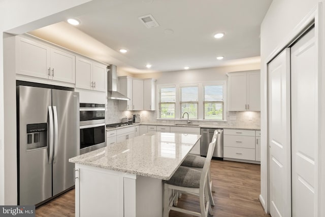 kitchen featuring visible vents, wall chimney exhaust hood, a sink, backsplash, and stainless steel appliances