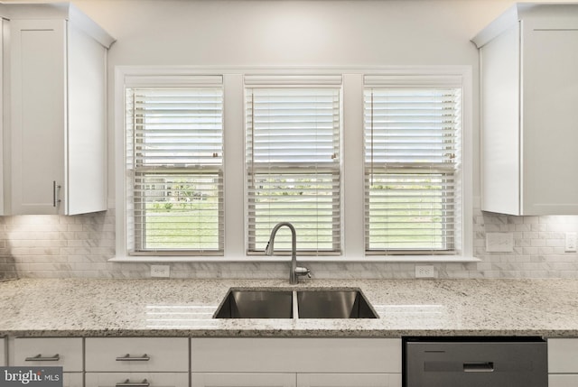 kitchen featuring white cabinetry, a sink, dishwashing machine, and tasteful backsplash
