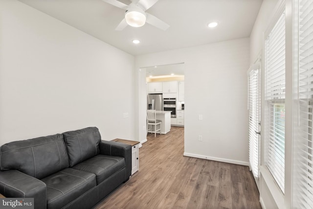 living area with baseboards, recessed lighting, ceiling fan, and light wood-style flooring