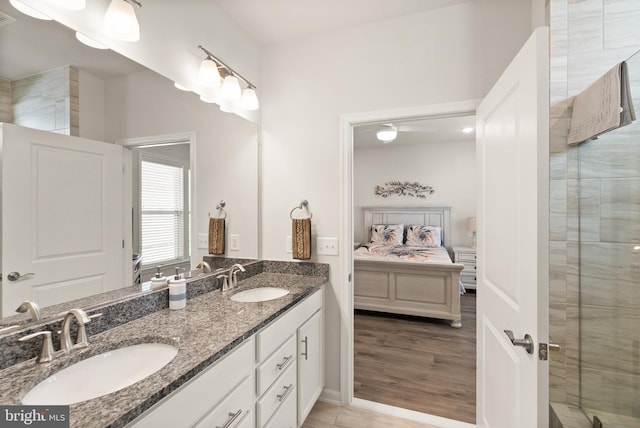 ensuite bathroom featuring double vanity, a tile shower, a sink, and ensuite bath