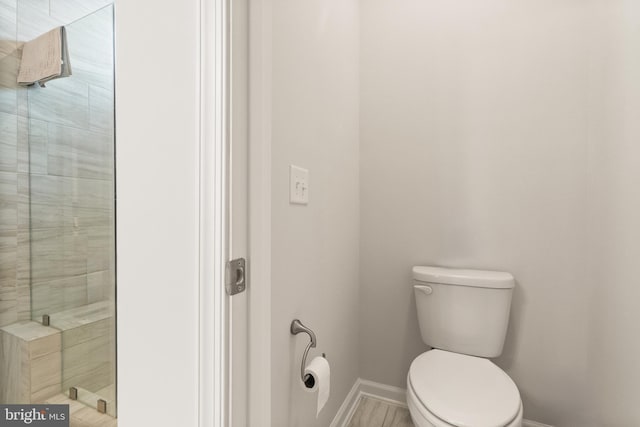 bathroom featuring baseboards, a tile shower, and toilet