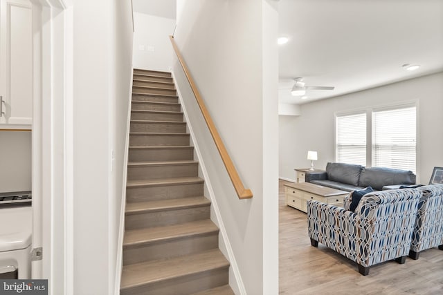 staircase featuring baseboards, washer / clothes dryer, ceiling fan, and wood finished floors