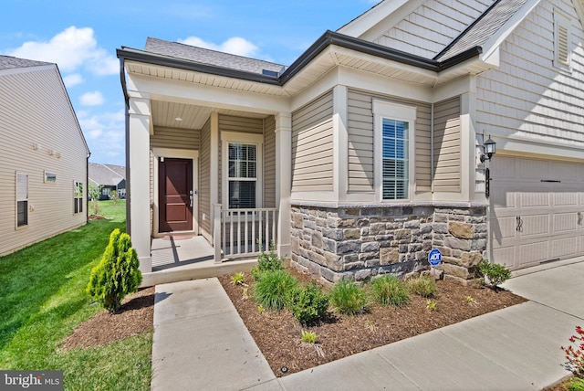entrance to property featuring roof with shingles, covered porch, a yard, and stone siding