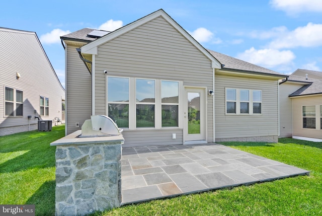 back of house featuring roof with shingles, area for grilling, a patio area, central air condition unit, and a yard