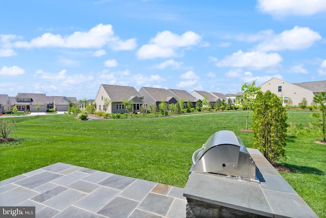 view of yard with a residential view, a patio, and an outdoor kitchen