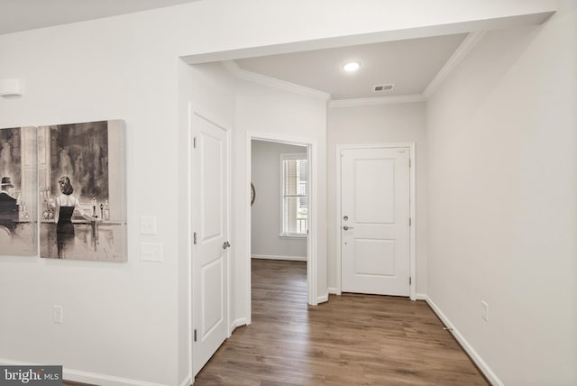 hall featuring visible vents, wood finished floors, baseboards, ornamental molding, and recessed lighting