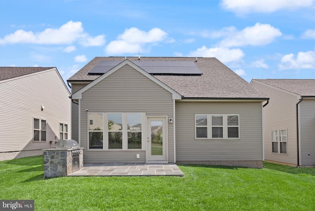 rear view of house with a yard, exterior kitchen, roof mounted solar panels, and a patio area