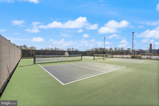 view of tennis court with community basketball court and fence