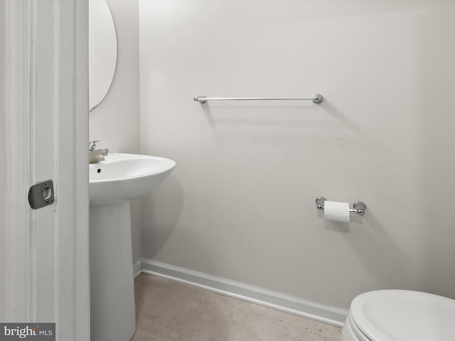 half bathroom featuring baseboards, tile patterned flooring, and toilet