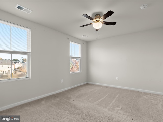 unfurnished room with baseboards, visible vents, light carpet, and ceiling fan