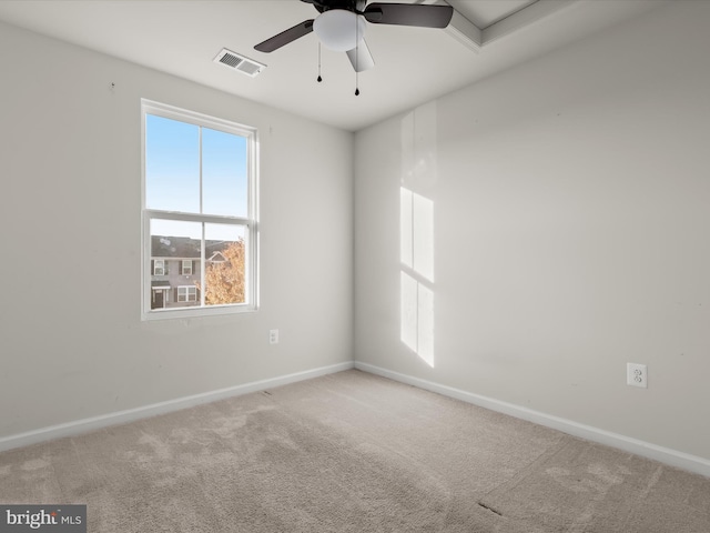 carpeted spare room featuring visible vents, baseboards, and ceiling fan