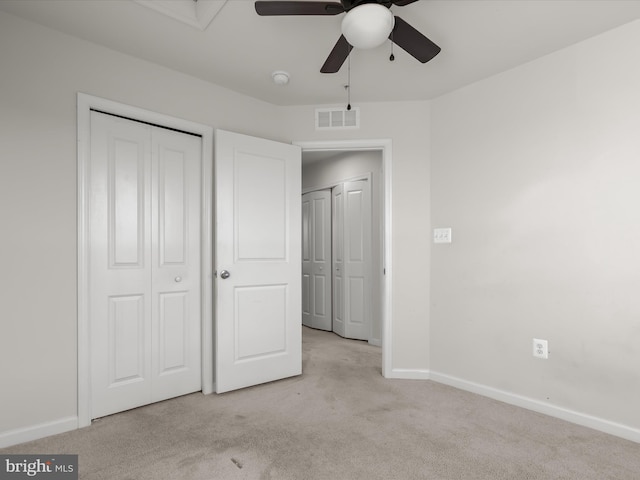 unfurnished bedroom with visible vents, a closet, baseboards, ceiling fan, and light colored carpet
