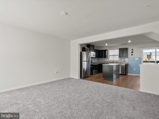 kitchen with backsplash, a center island, open floor plan, stainless steel appliances, and dark carpet