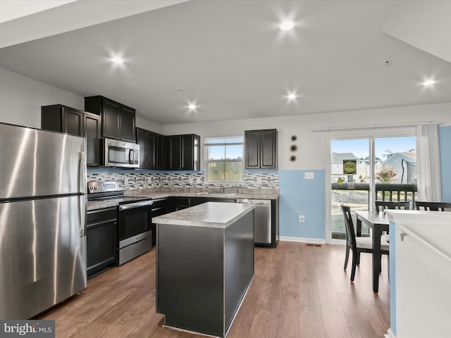kitchen with decorative backsplash, wood finished floors, a sink, light countertops, and stainless steel appliances