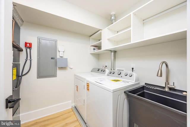 laundry area featuring electric panel, laundry area, independent washer and dryer, a sink, and light wood finished floors
