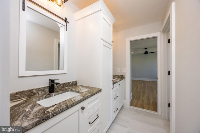 bathroom featuring ceiling fan, two vanities, and a sink