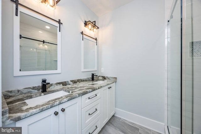 full bath with double vanity, baseboards, a shower stall, and a sink
