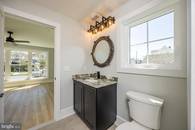 half bathroom featuring vanity, toilet, a ceiling fan, baseboards, and visible vents