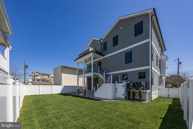 back of property featuring a lawn, a fenced backyard, a gate, and stairway