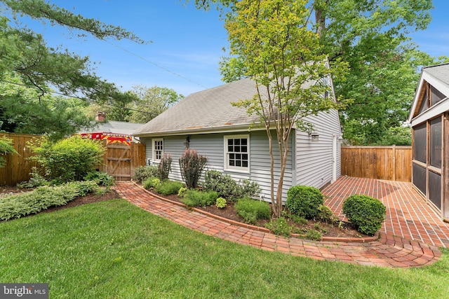 view of side of home featuring a gate, a sunroom, and roof with shingles