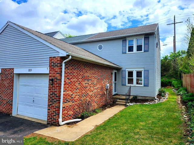 view of side of home with a lawn, fence, an attached garage, and brick siding