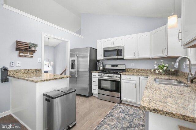 kitchen with light stone countertops, light wood-style floors, white cabinetry, a sink, and appliances with stainless steel finishes