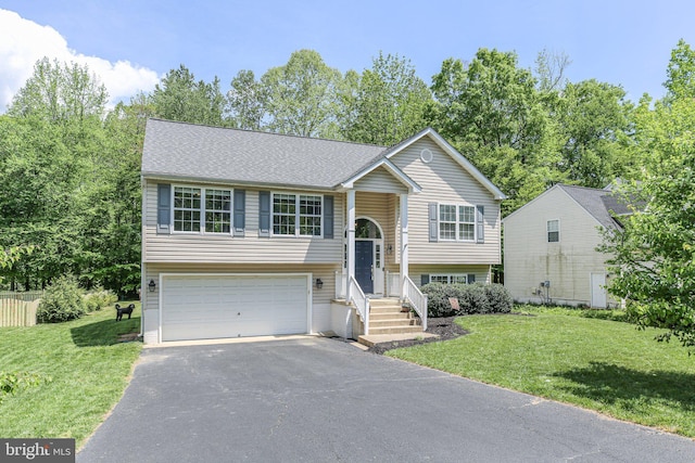 bi-level home with an attached garage, roof with shingles, driveway, and a front yard
