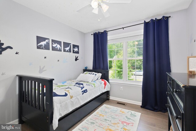 bedroom featuring baseboards, a ceiling fan, wood finished floors, and visible vents