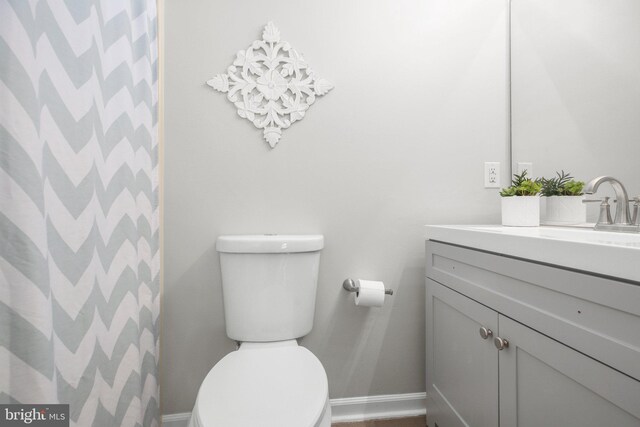 bathroom with vanity, baseboards, curtained shower, and toilet