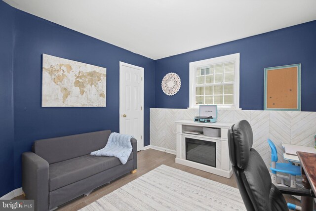 home office with a wainscoted wall, baseboards, and wood finished floors