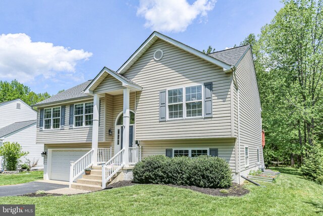 split foyer home with a garage, a shingled roof, driveway, and a front lawn