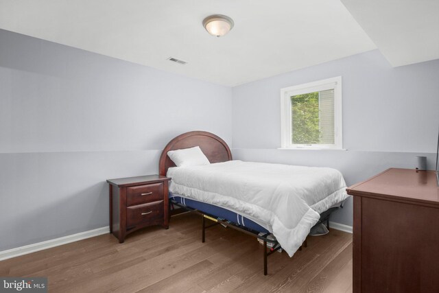 bedroom featuring visible vents, baseboards, and wood finished floors