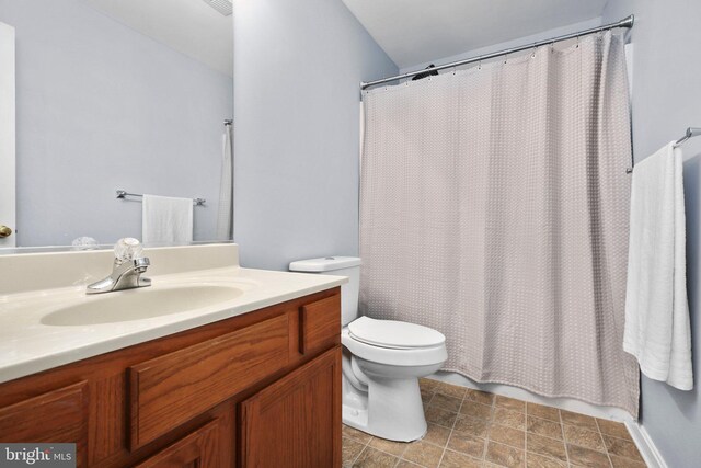 full bath featuring vanity, a shower with curtain, toilet, and stone finish flooring