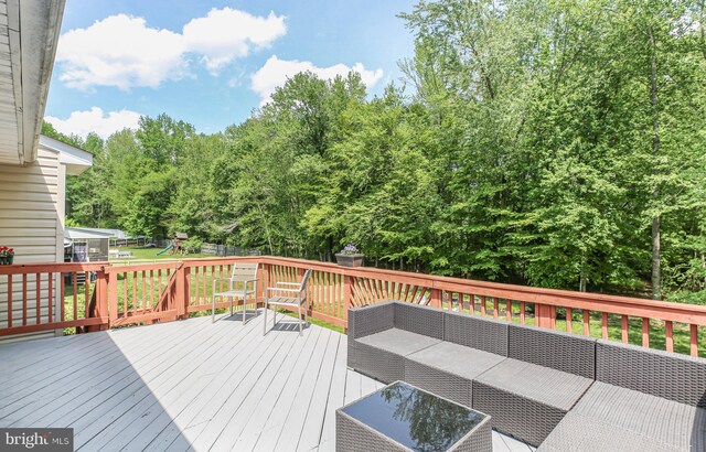 wooden deck featuring a playground, fence, and an outdoor hangout area