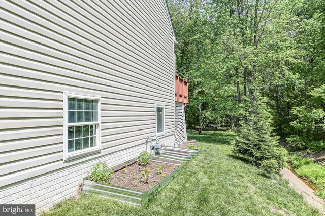 view of side of home with a yard and a garden