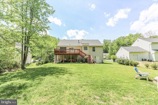 rear view of house featuring stairs, a lawn, and a wooden deck