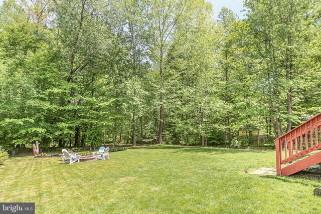 view of yard featuring a view of trees and an outdoor fire pit