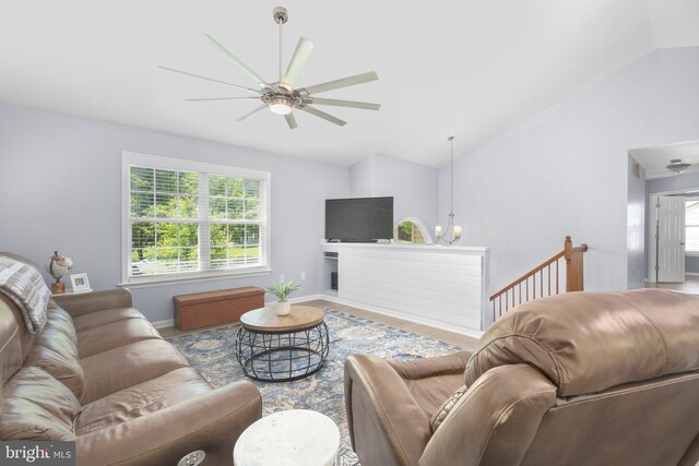 living area featuring wood finished floors, baseboards, ceiling fan with notable chandelier, and lofted ceiling