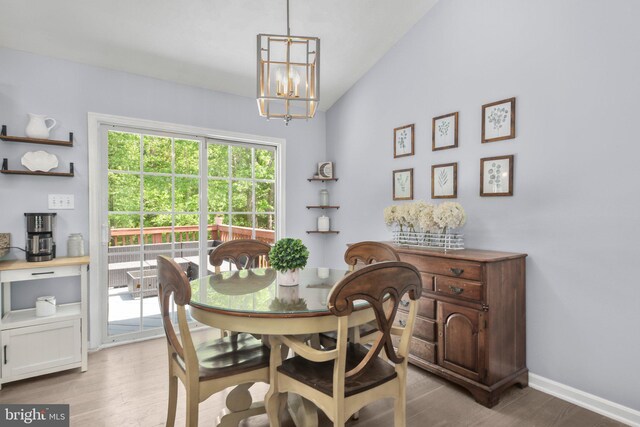 dining room featuring light wood-type flooring, baseboards, a notable chandelier, and vaulted ceiling