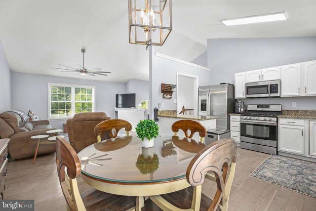 dining space featuring high vaulted ceiling, ceiling fan with notable chandelier, and light wood-style floors