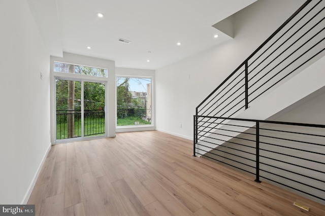 unfurnished living room featuring visible vents, stairs, wood finished floors, baseboards, and recessed lighting