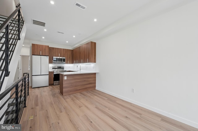 kitchen featuring light countertops, appliances with stainless steel finishes, brown cabinets, and visible vents