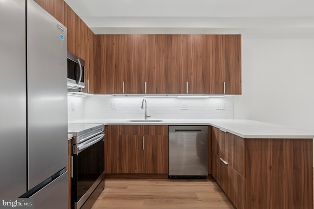 kitchen featuring a sink, appliances with stainless steel finishes, modern cabinets, and brown cabinets