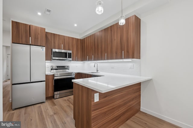 kitchen featuring visible vents, a sink, brown cabinetry, and appliances with stainless steel finishes