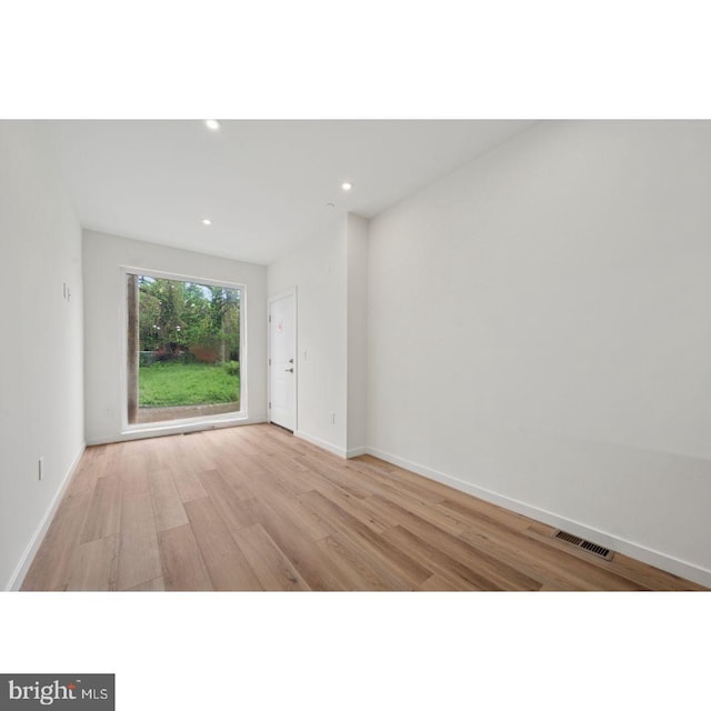 unfurnished room with recessed lighting, baseboards, wood finished floors, and visible vents