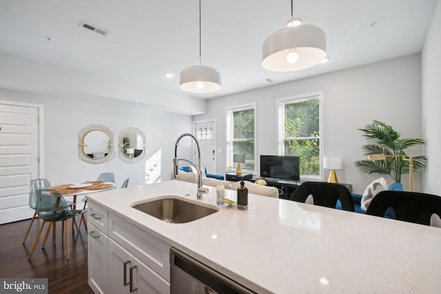 kitchen featuring dark wood-style flooring, decorative light fixtures, visible vents, stainless steel dishwasher, and a sink