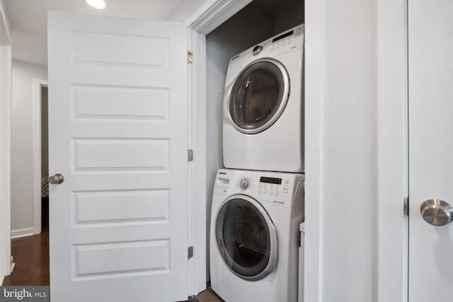 washroom featuring laundry area, stacked washing maching and dryer, and dark wood-style floors