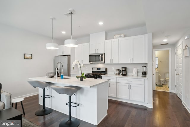 kitchen featuring white cabinets, a breakfast bar, light countertops, stainless steel appliances, and baseboards